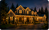 Second nighttime house mockup showing a warmly illuminated roofline.