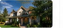 Daytime exterior photograph of a light gray multi-gabled house and green yard.